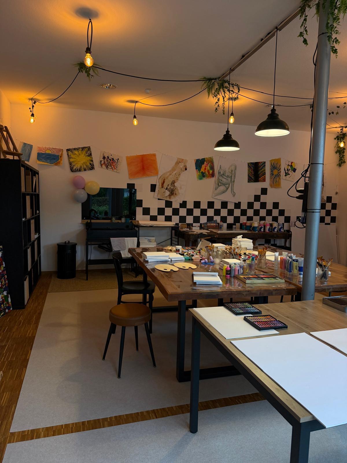 Atelier von The Way of Art: Maltische mit Farben, Pastellkreiden und Bildern an der Wand